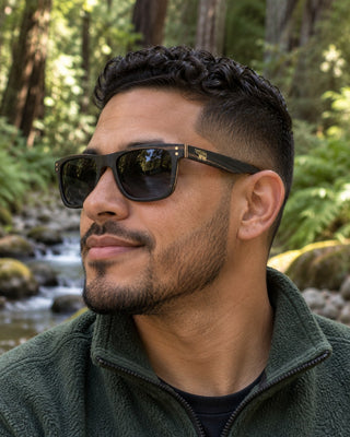 Big Basin polarized sunglasses worn by a man beside a fern-lined creek in a redwood forest