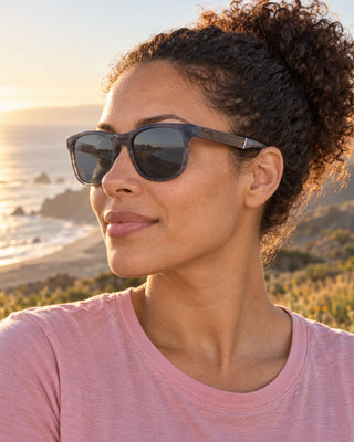 Lost Coast polarized sunglasses worn by a woman on a grassy bluff above the Lost Coast at golden hour