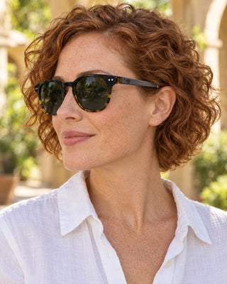 Palo Alto polarized sunglasses worn by a woman in a sunny garden courtyard in Palo Alto